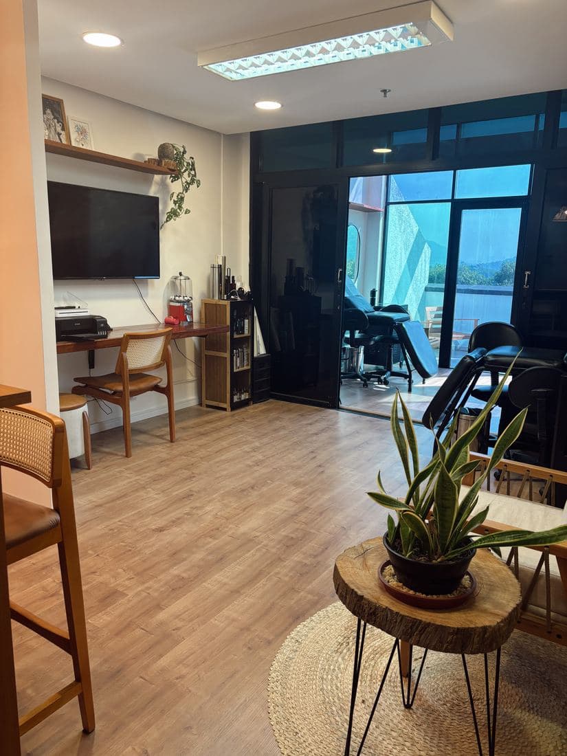 Sala de espera com mesa de tronco, plantas e tapete de palha